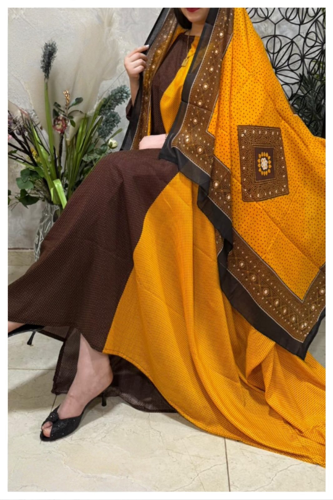 ثوب قطني بلون أصفر وعنابي، مزين بتصميم جميل مطبوع عليه شيلة متناسقة، ومخيط على الطراز الظفاري