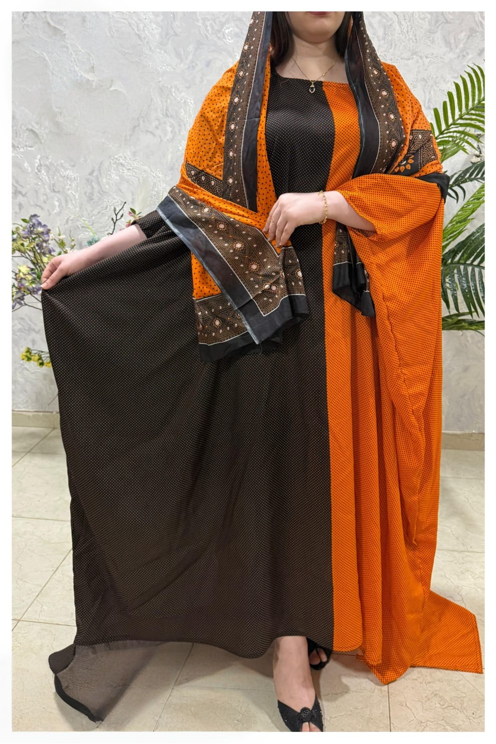 ثوب قطني بلون برتقالي وبني، مزين بتصميم جميل مطبوع عليه شيلة متناسقة، ومخيط على الطراز الظفاري