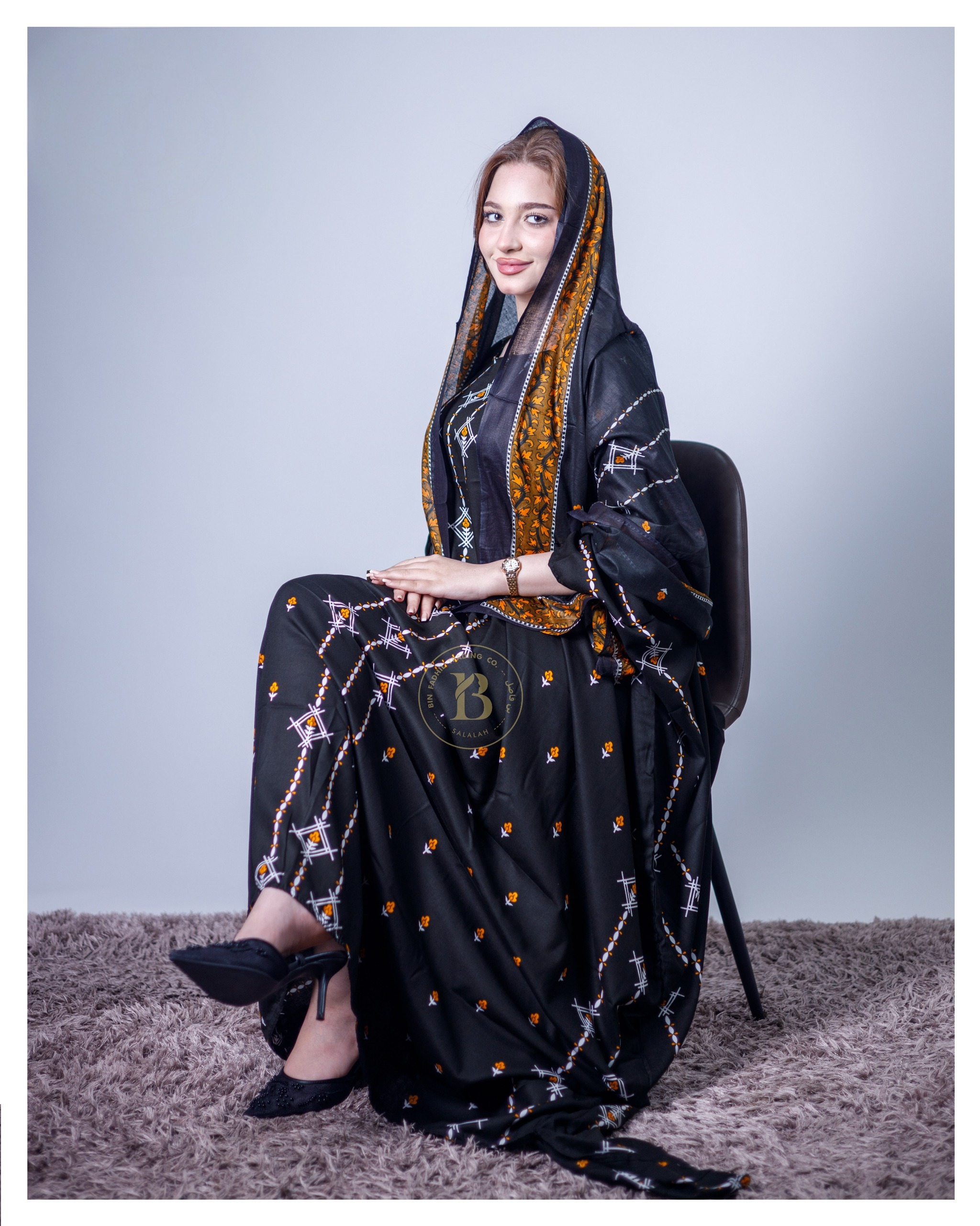 ثوب أسود اللون مصنوع من القطن، مزين بتصميم جميل مطبوع عليه شيلة متناسقة، ومخيط على الطراز الظفاري